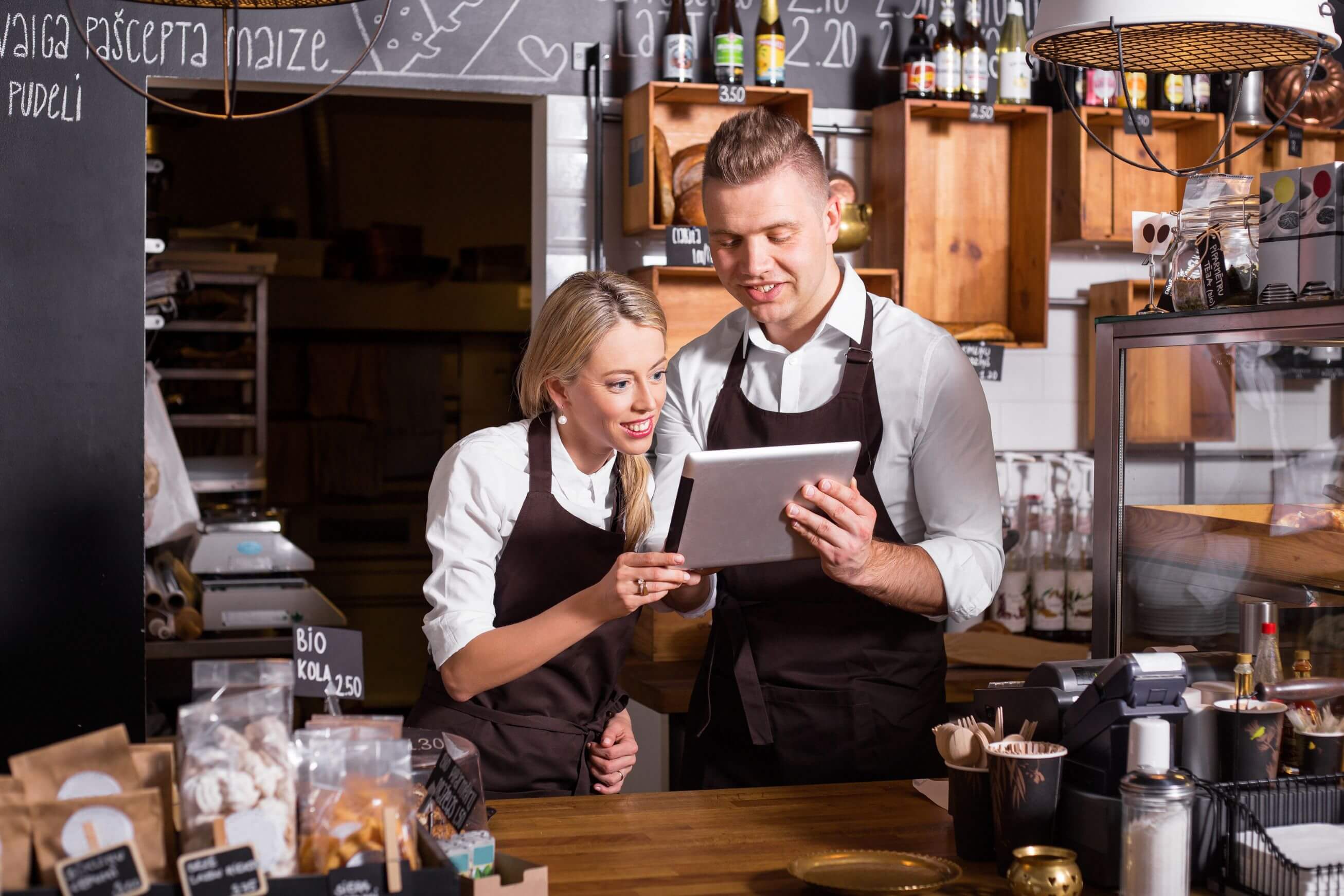 Business owner with systemised business that runs without them Cafe business team happily reviewing operations on a tablet, illustrating how to systemise your business successfully.